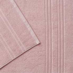 Blush pink cotton towels with ribbed border detail, shown folded and layered to display texture and weight