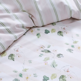Christys green floral leaf print duvet set with green stripe pillowcase, shown in a styled bed close-up
