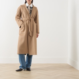 Model wearing Max Mara camel wool belted coat, styled with blue wide-leg jeans and a printed shirt.