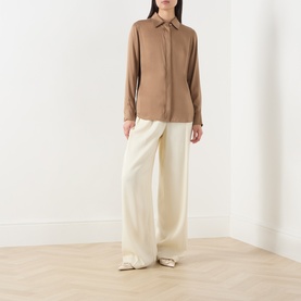 Model wearing Max Mara Studio tobacco silk shirt with concealed placket, styled with wide-leg cream trousers and ivory flat mules.