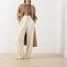 Model wearing Max Mara Studio Tobacco silk shirt, styled with cream wide-leg trousers and a camel longline coat.