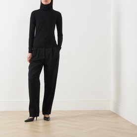 Model wearing Max Mara Main black wool turtleneck top, styled with black wide-leg trousers and black pointed-toe heels.