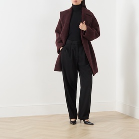 Model wearing Max Mara Main black wool turtleneck top, styled with burgundy coat and black tailored trousers.