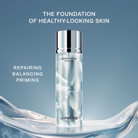 La Prairie Swiss Pristine Essence 150ml toner in frosted glass bottle with silver cap, displayed against a soft blue background with water elements.