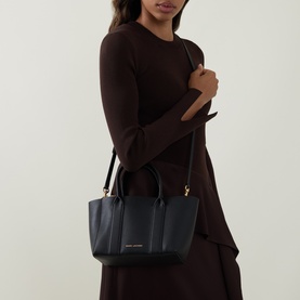 Model carrying Marc Jacobs The Small Work Tote Bag in black pebbled leather with gold-tone hardware and crossbody strap, styled with a dark burgundy