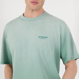 Model wearing Represent T-Shirt in Washed Aloe, featuring small chest logo print, relaxed fit, short sleeves, crew neck.
