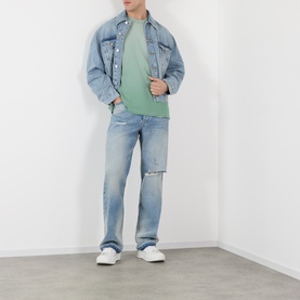 Model wearing Represent Washed Aloe T-shirt styled with light blue distressed denim jacket and matching jeans, white trainers.