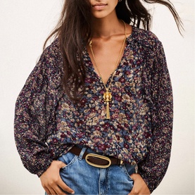 Model wearing Bash blue floral print V-neck blouse with puff sleeves, styled with light-wash jeans and brown belt