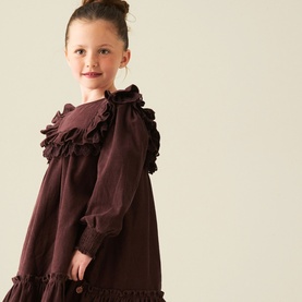 Model wearing Angel & Rocket chocolate cotton dress with ruffle collar and long sleeves, tiered hem detail