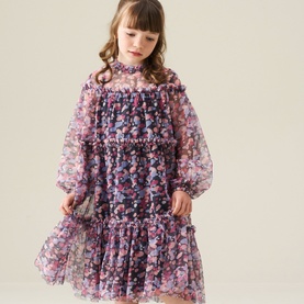 Model wearing floral purple chiffon tiered dress with sheer long sleeves, ruffle neckline and hem detailing