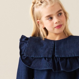 Model wearing Angel & Rocket Denim Blue cotton dress with layered ruffle collar detail, close-up shot on young girl.