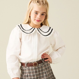 Model wearing Angel & Rocket white cotton shirt with black-trimmed double Peter Pan collar, styled with checked skirt and brown belt
