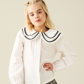 Model wearing Angel & Rocket white cotton shirt with oversized Peter Pan collar trimmed in black scalloped lace detail, styled with checked skirt