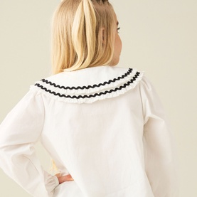Model wearing Angel & Rocket white cotton shirt, back view showing oversized collar with black ric-rac trim detail