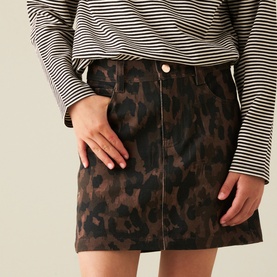 Model wearing brown leopard-print mini skirt with gold-tone button detail, styled with a black and white striped long-sleeve top.