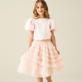 Model wearing Angel & Rocket blush tiered ruffle tulle midi skirt, styled with a matching pink puff-sleeve floral top.