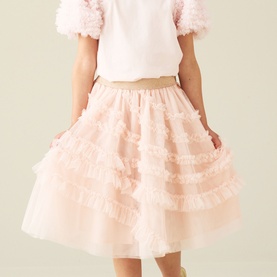 Model wearing Angel & Rocket blush tiered ruffle tulle skirt, styled with a white top and pink puff-sleeve overlay