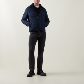Model wearing Belstaff Dark Ink quilted casual jacket with black knitwear, dark grey trousers and black leather boots.