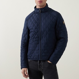 Model wearing Belstaff quilted casual jacket in Dark Ink navy, featuring zip front, buckle collar, and logo patch sleeve