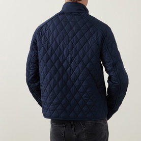 Model wearing Belstaff Dark Ink quilted casual jacket, back view, showing diamond quilt pattern and stand collar, styled with grey jeans.
