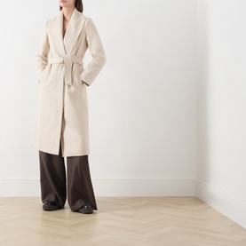 Model wearing Max Mara Studio ecru virgin wool belted wrap coat, styled with dark brown wide-leg trousers and black heels.