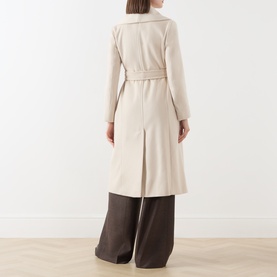 Model wearing Max Mara Studio ecru virgin wool coat, back view, with belted waist and midi length, styled with wide-leg dark trousers