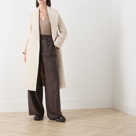 Model wearing Max Mara Studio ecru virgin wool coat, styled with brown wide-leg trousers and a neutral knit top.
