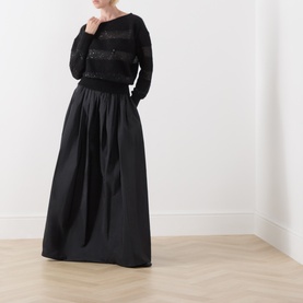 Model wearing Max Mara Studio Divo Metallic-Yarn Striped Sweater in black with boat neck, styled with a full-length black satin skirt.