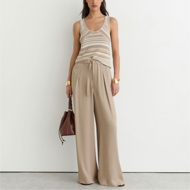 Model wearing Reiss beige wide-leg trousers with drawstring waist, styled with a striped knit tank top and brown leather bag.