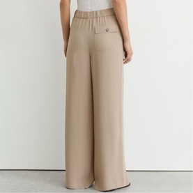 Model wearing Reiss beige wide-leg trousers, rear view showing elasticated waistband and relaxed silhouette
