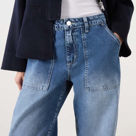 Model wearing LAgence Atlantis wide-leg jeans in mid-blue denim with large patch pockets, styled with a navy blazer.