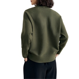 Model wearing Phase Eight dark green ribbed knit sweater, back view, styled with black wide-leg trousers