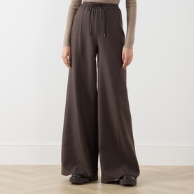 Model wearing Max Mara Main mud wide-leg wool trousers with drawstring waist, styled with a beige knit top and black shoes.