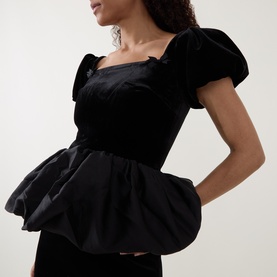Model wearing Self-Portrait black velvet puff-sleeve mini dress with structured peplum skirt and square neckline.