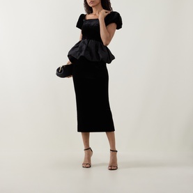Model wearing Self-Portrait black midi dress with peplum bodice, puff sleeves, and fitted skirt, styled with black heeled sandals and clutch bag.