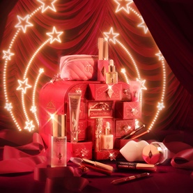 Charlotte Tilbury Beauty All Advent Calendar featuring red star-printed boxes, makeup products, and a pink cosmetic pouch