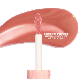 Charlotte Tilbury lip gloss with diamond tip applicator shown with a sheer nude-pink swatch, highlighting precise application feature