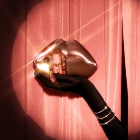 Charlotte Tilbury Beauty All Make Up Set in gold lip-shaped compact with black handle, against pink draped fabric background