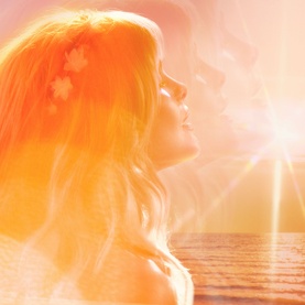 Charlotte Tilbury fragrance set lifestyle image featuring warm golden sunset backdrop with glowing light and floral hair details