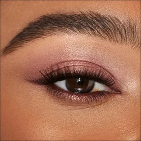 Close-up of an eye wearing Charlotte Tilbury make-up look featuring rosy pink shimmer eyeshadow and defined lash line
