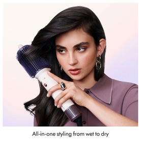 Model using Dyson Airsmooth Styling Brush on long dark hair, held at roots, cream and navy colourway