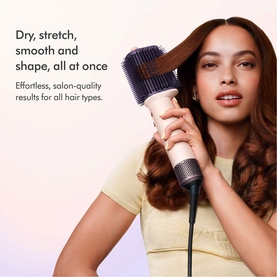 Model using Dyson AirsmoothTM Styling Brush on long wavy hair, styled in a yellow top against a soft gradient background.