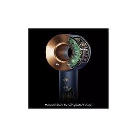 Close-up of Dyson hair dryer nozzle attachment in gold and navy, showing internal heat sensor technology