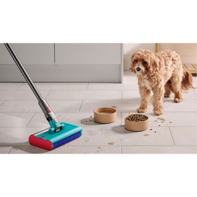 Dyson V15 Submarine vacuum with wet mop head cleaning tiled floor beside a dog and pet food bowls