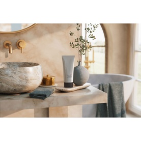 Rituals Shower Gel tube displayed on marble surface in neutral bathroom setting with vase, candle and folded towels