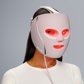 Model with Shark Beauty CryoGlow LED Face Mask in Spa Pink, shown active with red light therapy illuminated across eye and cheek zones