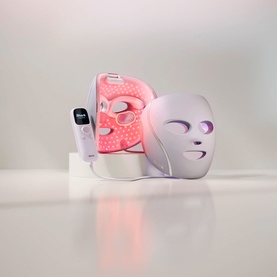 Shark Beauty CryoGlow LED Face Mask in Spa Pink, shown illuminated with pink and white LED lights, with handheld controller.