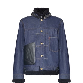 Sacai indigo denim casual jacket with black shearling collar and cuffs, contrast leather pocket, gold buttons, and white topstitching.