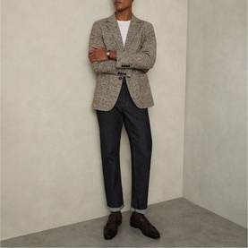 Model wearing Reiss raw indigo straight-leg jeans styled with a brown tweed blazer, white tee and dark brown leather shoes