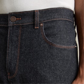 Model wearing Reiss raw indigo jeans, close-up of front pocket detail with contrast orange stitching and copper button